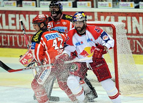 #47 Darryl Bootland, Stuermer, Red Bull Salzburg, vor dem Tor des KAC, bedraengt von Jeff Tory, dahinter Tormann Travis Scott, KAC.