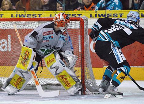 #27 Bernhard Bock, im Tor der Graz 99ers, der Linzer #20 Brad Purdie, Liwest Black Wings Linz, am Weg hinter das Tor.